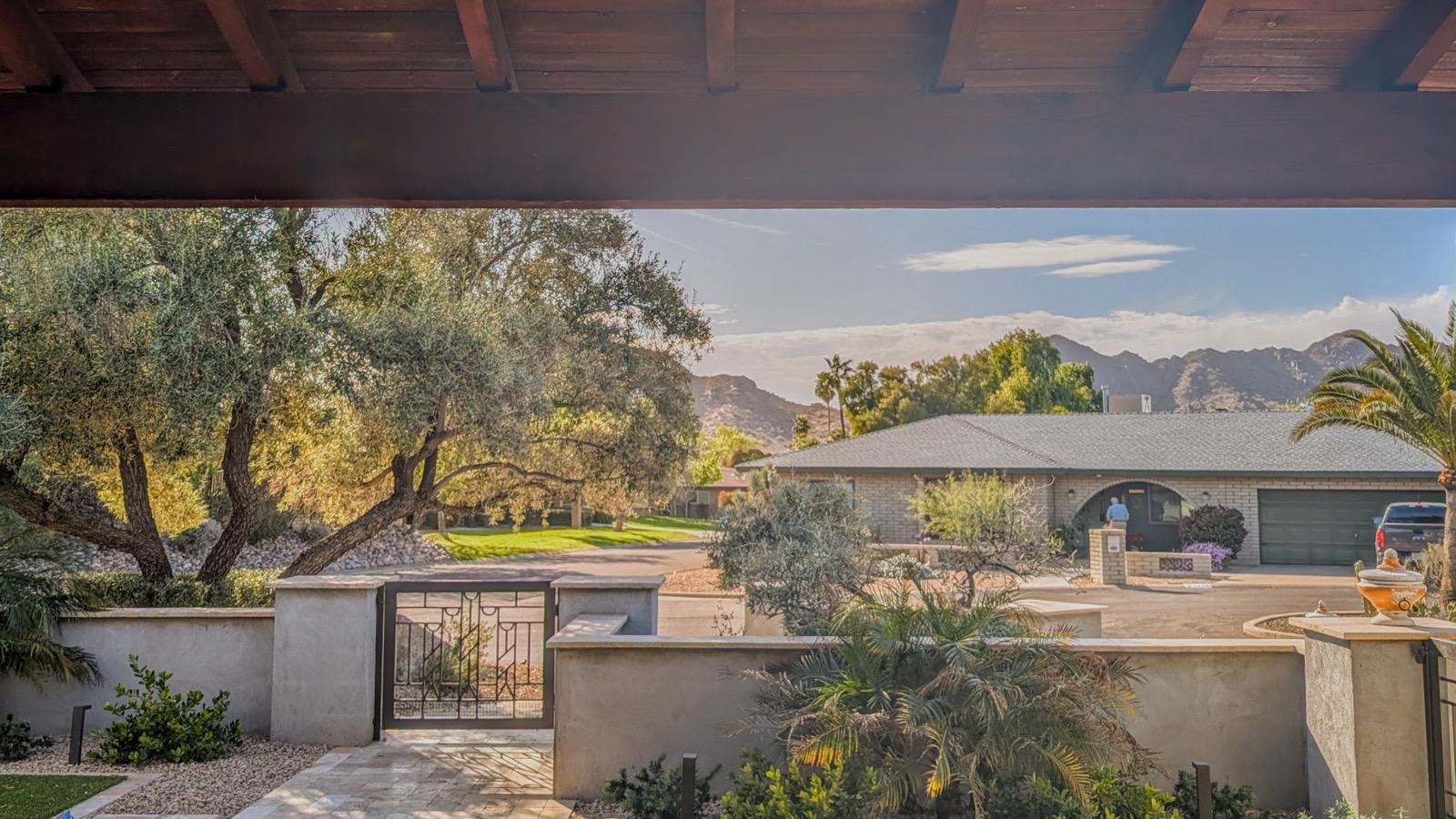 Mission project front courtyard after — stone walkways, iron gate, fountain, and palms