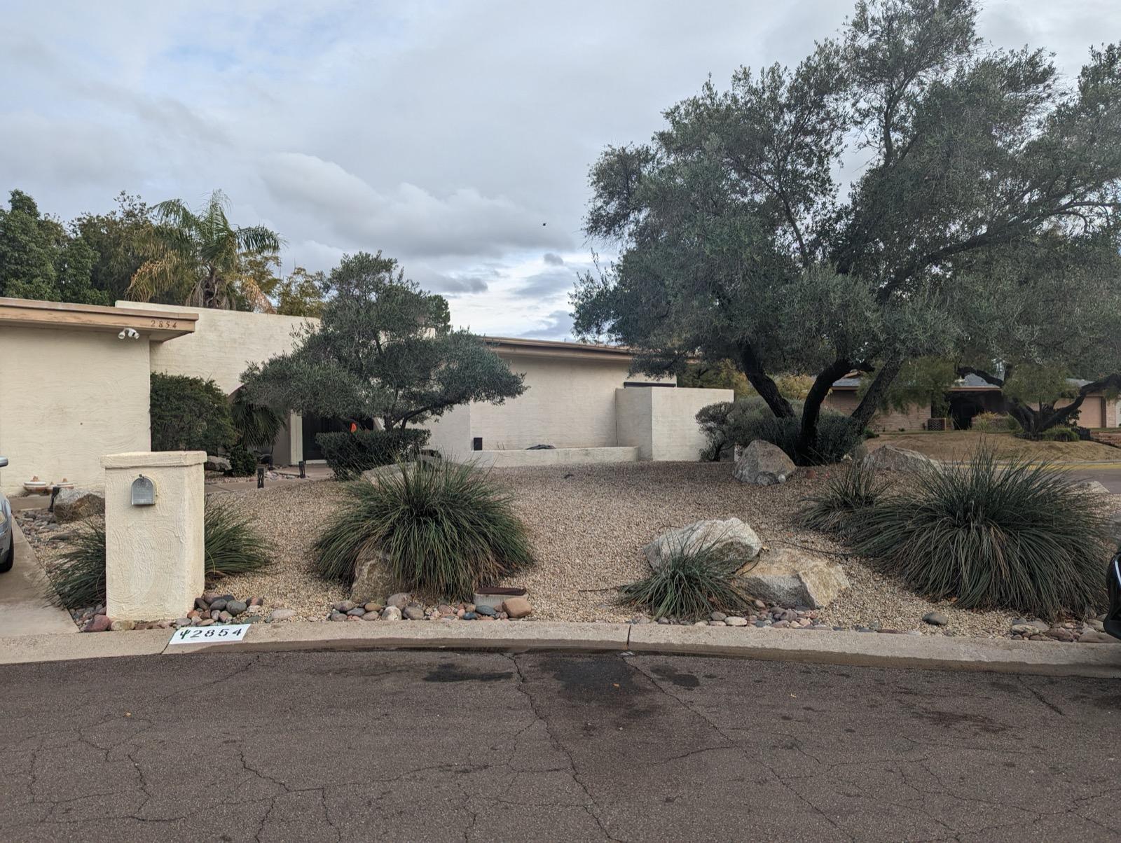 Mission project exterior before renovation — dated stucco facade with gravel approach